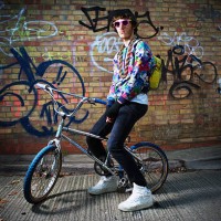 young man sitting on bike. - fashion stock-fotos und bilder