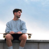 young man sitting with a skateboard in a cloudy day at sunset - fashion photos et images de collection