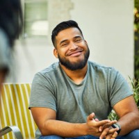 young man smiling in yard during social gathering - garden decoration photos et images de collection