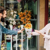 young man taking a flower bouquet from a senior florist - garden decoration stock pictures, royalty-free photos & images