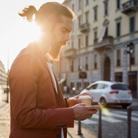 young man with coffee to go looking at cell phone - junk food stock pictures, royalty-free photos & images