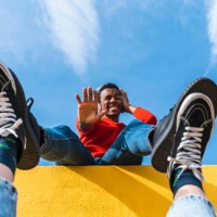 young man with headphones, dancing for person, leaning on yellow wall - fashion stock-fotos und bilder