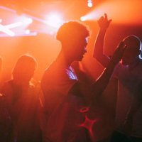 young men and women dancing against illuminated red spotlights at nightclub - concert stock pictures, royalty-free photos & images