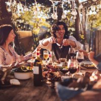 young multi-ethnic friends dining at rustic countryside restaurant at sunset - food stock pictures, royalty-free photos & images