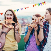 young people eating pizza on a rooftop party - junk food stockfoto's en -beelden