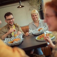 young people enjoy eating unhealthily in a fast food restaurant. - junk food stock pictures, royalty-free photos & images
