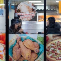 Young people sitting down inside to eat in a fast food restaurant where images of the foods available adorn the exterior on 14th December 2023 in...