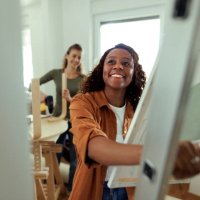 young smiling woman deciding where to put picture in new apartment - home decoration stock pictures, royalty-free photos & images