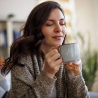 young smiling woman enjoying in smell of fresh coffee at home - coffee stock pictures, royalty-free photos & images