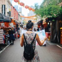 young solo traveler woman in singapore street market checking the map - travel stock pictures, royalty-free photos & images