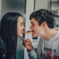young teenager copule sharing slice of pizza at home - food stock pictures, royalty-free photos & images
