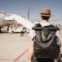 young white man with hat and suitcase walking through the airport on the runway towards his airplane - travel stock pictures, royalty-free photos & images