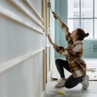 young woman applying paint on wall in apartment - home decoration stock pictures, royalty-free photos & images