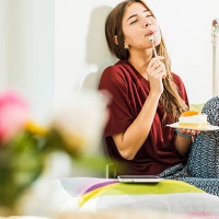 young woman at home enloying piece of cake in bed - food stock pictures, royalty-free photos & images
