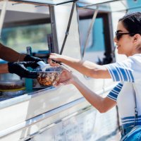 young woman buying take away food from a street food stand - junk food stock pictures, royalty-free photos & images