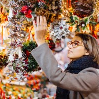 young woman choosing christmas decoration on a christmas market in barcelona, spain - home decoration stock pictures, royalty-free photos & images