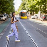 young woman crossing the street with mobile phone. - fashion photos et images de collection