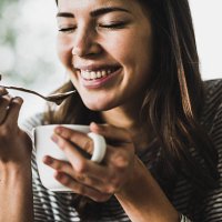 young woman drinking cappuccino, spooning milk froth - coffee stockfoto's en -beelden