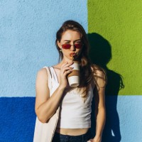 young woman drinking coffee against squared color wall. - fashion stock pictures, royalty-free photos & images
