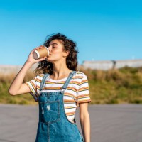 young woman drinking coffee from a disposable cup - junk food stock pictures, royalty-free photos & images