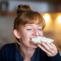 young woman eating bread with cream cheese - food stock pictures, royalty-free photos & images