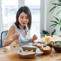 young woman eating healthy takeaway meal at home - junk food stock pictures, royalty-free photos & images
