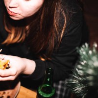 young woman eating homemade pizza with beer sitting by christmas tree - food stock pictures, royalty-free photos & images