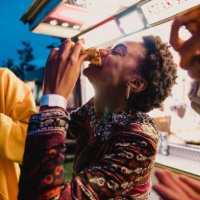 young woman eating pizza at festival - junk food stock pictures, royalty-free photos & images