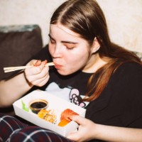 young woman eating sushi at house party - junk food stock pictures, royalty-free photos & images