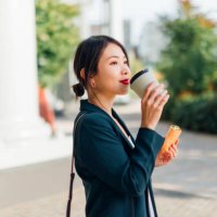 young woman eating wrap sandwich on lunch break outdoors - junk food stock pictures, royalty-free photos & images