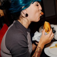 young woman enjoying a burger at home with her dog watching - junk food stock pictures, royalty-free photos & images