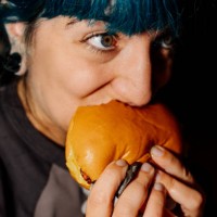 young woman enjoying a delicious burger at home: food delivery - junk food stock pictures, royalty-free photos & images