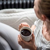 young woman enjoying coffee and relaxing on a sofa - coffee stock pictures, royalty-free photos & images