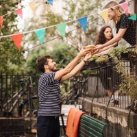 young woman giving food to smiling male friend from balcony during garden party - garden decoration stock pictures, royalty-free photos & images