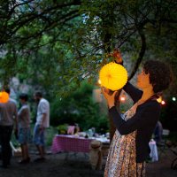 young woman hanging paper lantern on tree in back yard - garden decoration stock pictures, royalty-free photos & images
