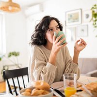 young woman having breakfast at home drinking coffee - coffee stockfoto's en -beelden