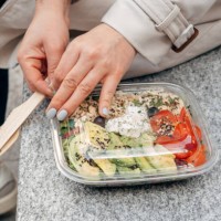 young woman holding a large portion of takeaway salad with chicken, avocado tomato and feta cheese, takeaway food , woman eating lunch outside outside the office - junk food stock pictures, royalty-free photos & images