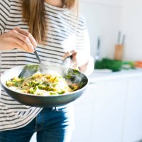 young woman holding pan with vegan pasta dish - food stock pictures, royalty-free photos & images