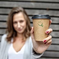 young woman holding takeaway coffee cup with smiley face - junk food stock pictures, royalty-free photos & images