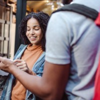 young woman holds the ordered food and signs the receipt on the smart phone - junk food stock pictures, royalty-free photos & images