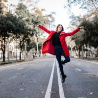 young woman in red jacket with arms raised dancing on street - fashion stock pictures, royalty-free photos & images