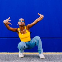 young woman in squatting in front of blue wall - fashion stock pictures, royalty-free photos & images