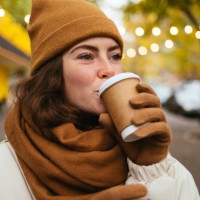 young woman in warm clothing drinking coffee on street during autumn - junk food stock pictures, royalty-free photos & images