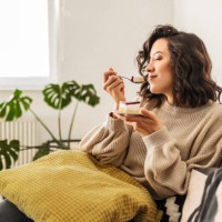 young woman is sitting in the living room alone enjoying taste of the cake - food stock pictures, royalty-free photos & images