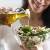 young woman pouring olive oil in to the salad. healthy lifestyle eating concept. - food stock pictures, royalty-free photos & images
