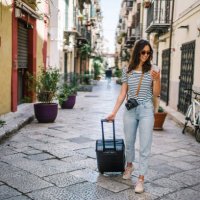 young woman pulls suitcase down cobblestone street - travel stock pictures, royalty-free photos & images