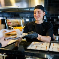 young woman's first day working at a burger restaurant - junk food stock pictures, royalty-free photos & images