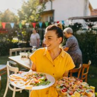 young woman serving food at outdoors dinner party - food stock pictures, royalty-free photos & images