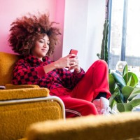 young woman sitting indoors, using smartphone - fashion stock pictures, royalty-free photos & images