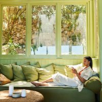 young woman sitting on her sofa and texting on her phone - home decoration stock pictures, royalty-free photos & images